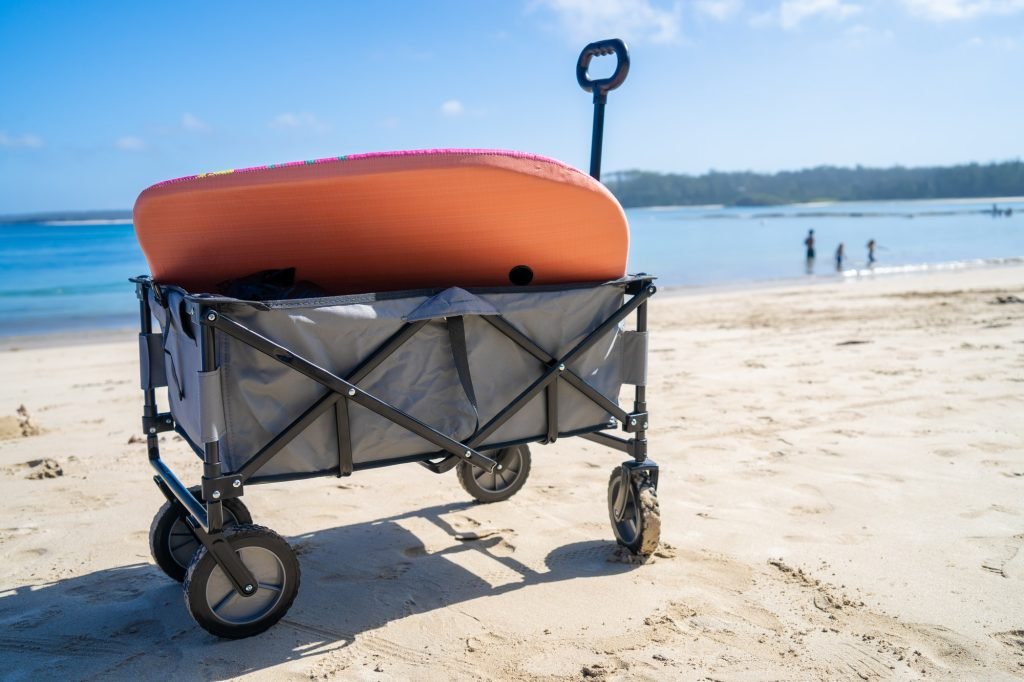 Beach cart beach wagon on sandy beach near the ocean bay. Family vacation